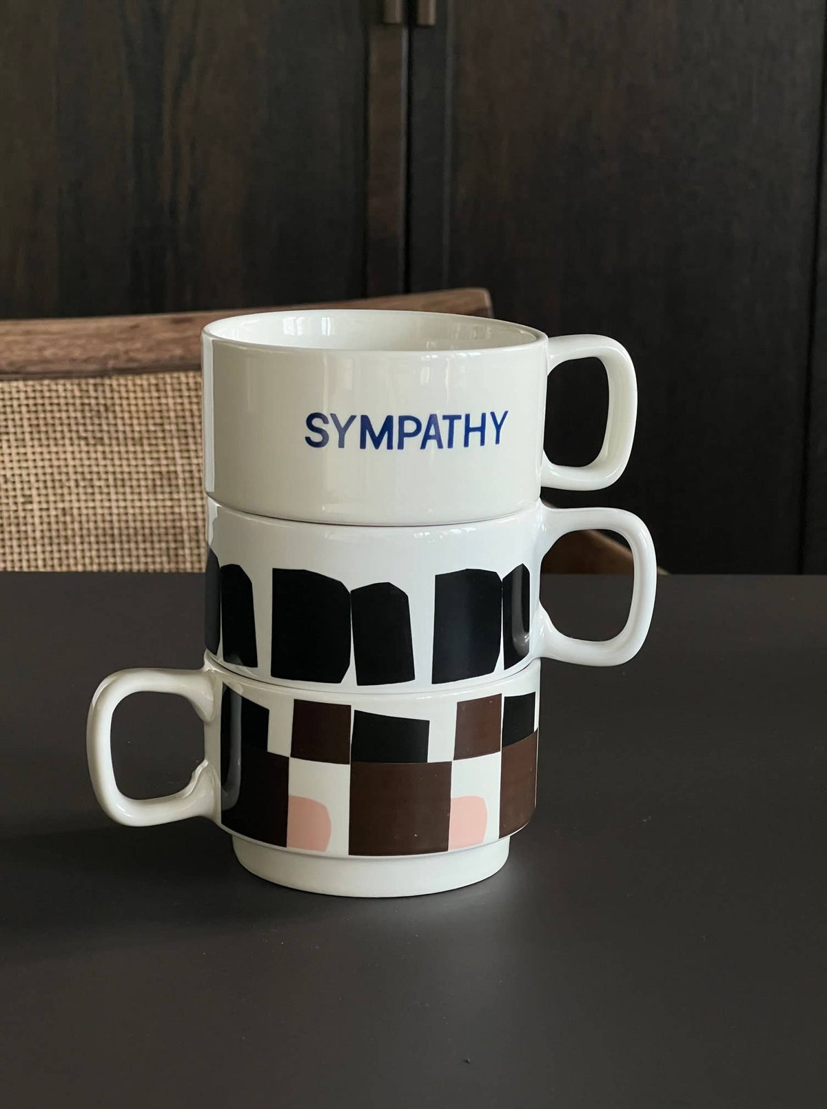 Χειροποίητη κεραμική κούπα σε off-white χρώμα με μαύρο αφηρημένο γραφικό σχέδιο και γυαλιστερό φινίρισμα.