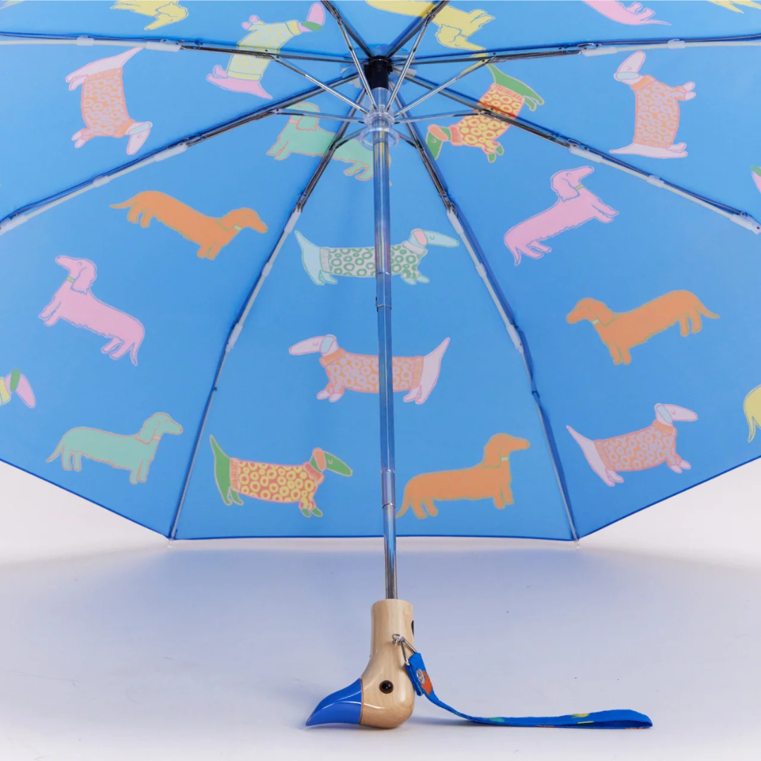 Αναδιπλούμενη ομπρέλα Original Duckhead Dogs In Blue σε μπλε φόντο με εικονογραφημένους σκύλους και χειροποίητη ξύλινη λαβή πάπιας.