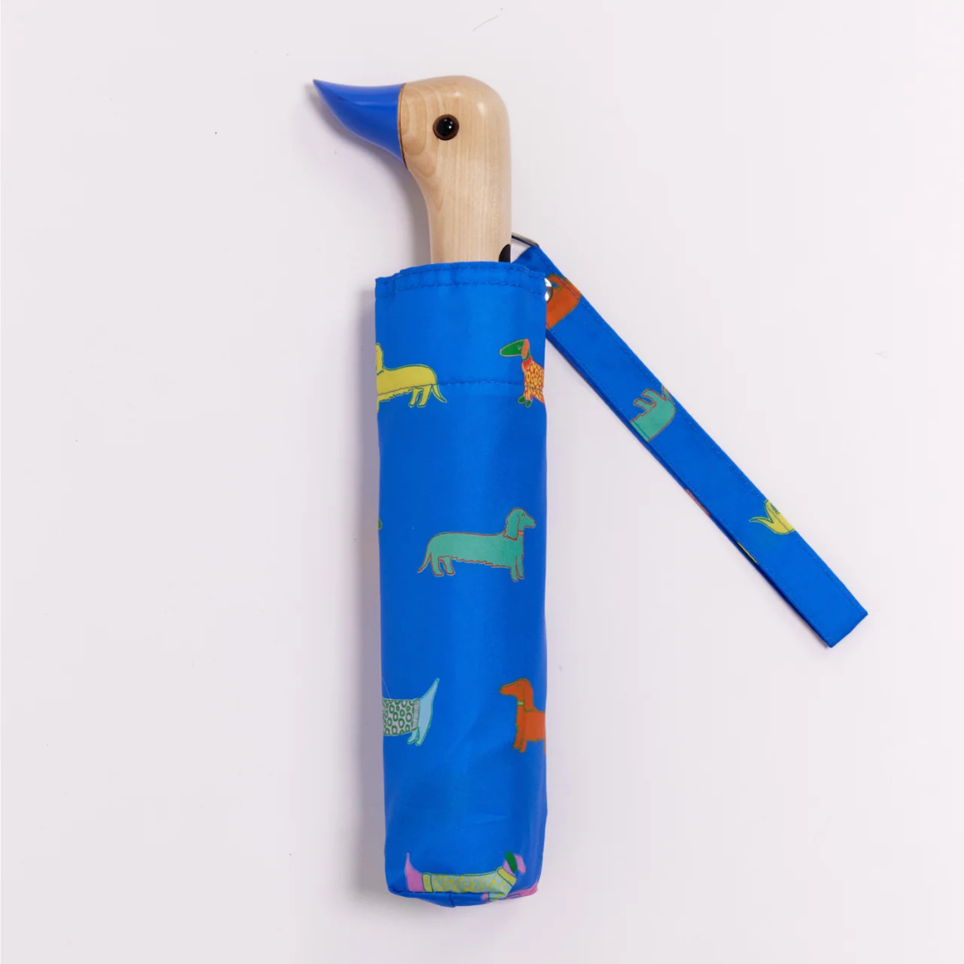 Αναδιπλούμενη ομπρέλα Original Duckhead Dogs In Blue σε μπλε φόντο με εικονογραφημένους σκύλους και χειροποίητη ξύλινη λαβή πάπιας.