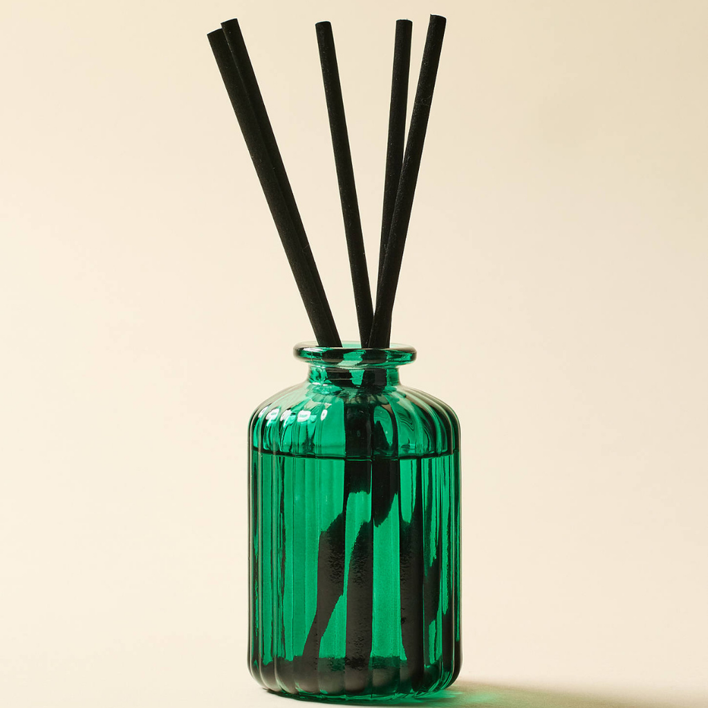 Πράσινος ραβδωτός γυάλινος διαχυτής αρώματος Balsam & Fir 147ml με μαύρες ράβδους (fiber reeds) και την εικονογραφημένη συσκευασία του.