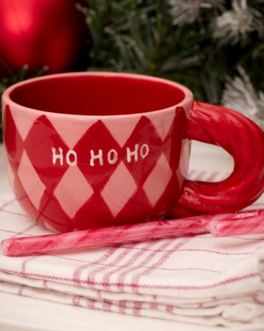 Χειροποίητη κεραμική κούπα Qué Rico Natalia με πολύχρωμο μοτίβο Harlequin σε κόκκινο και ροζ, και χαρακτηριστική στριφτή λαβή.